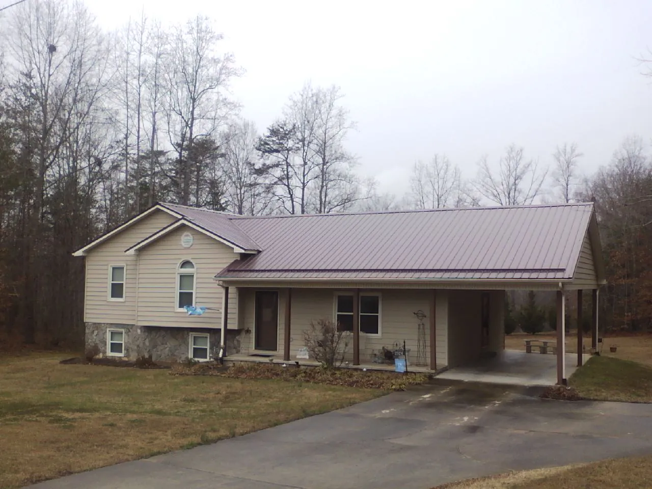 Burgundy metal roof on a tan split level home with an attached carport in Crawford